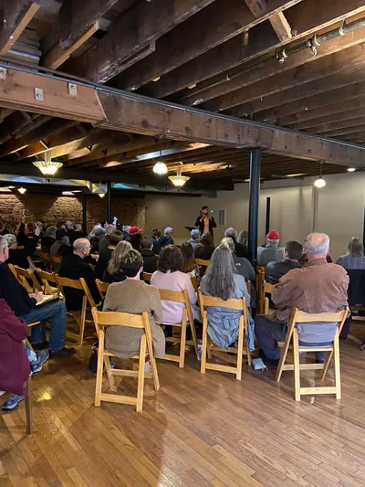 A gathering seated in a hall with wooden beams