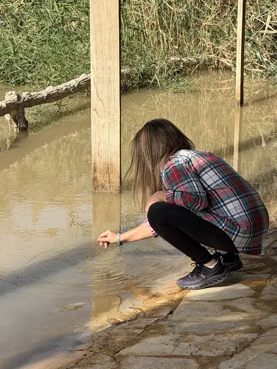 A person kneeling at the edge of a river